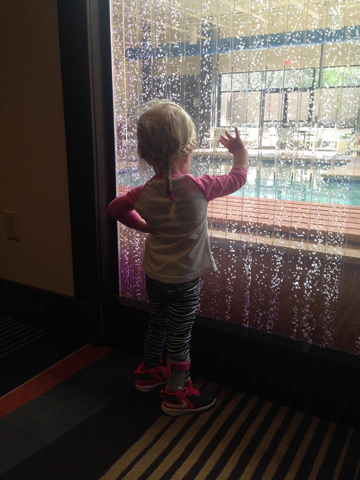 admiring a waterfall wall and holding her right hand open on her own which is a rare occurrence
